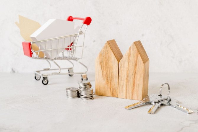 wooden-house-blocks-stack-coins-keys-small-shopping-cart-concrete-backdrop.jpg