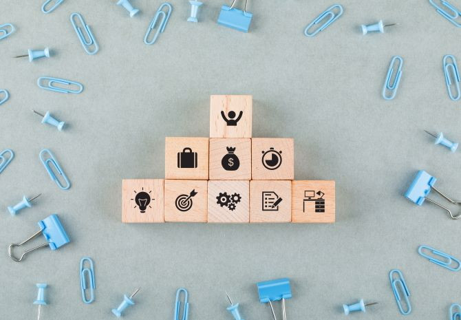 conceptual-business-office-with-wooden-blocks-with-icons-paperclips-binder-clips-top-view.jpg