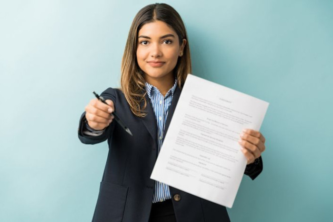 confident-young-female-professional-with-contract-pen-against-colored-background.jpg