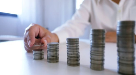 midsection-businesswoman-stacking-coins-table-office.jpg