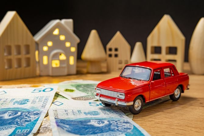 toy-car-with-polish-money-wooden-house-increasing-life-expenses-inflation-crisis.jpg